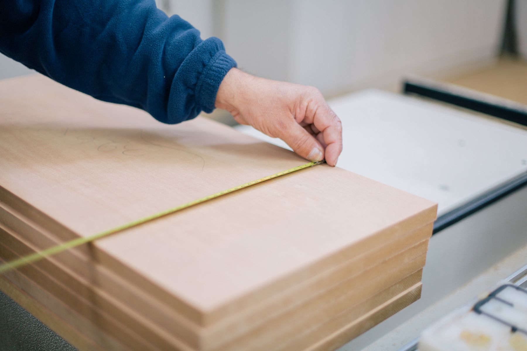 Carpenter measuring a wood panel with a tape measure
