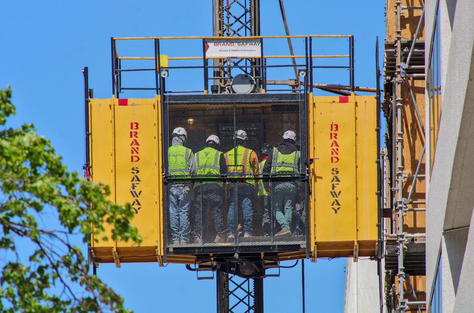 Commercial construction crew riding a building-site material lift