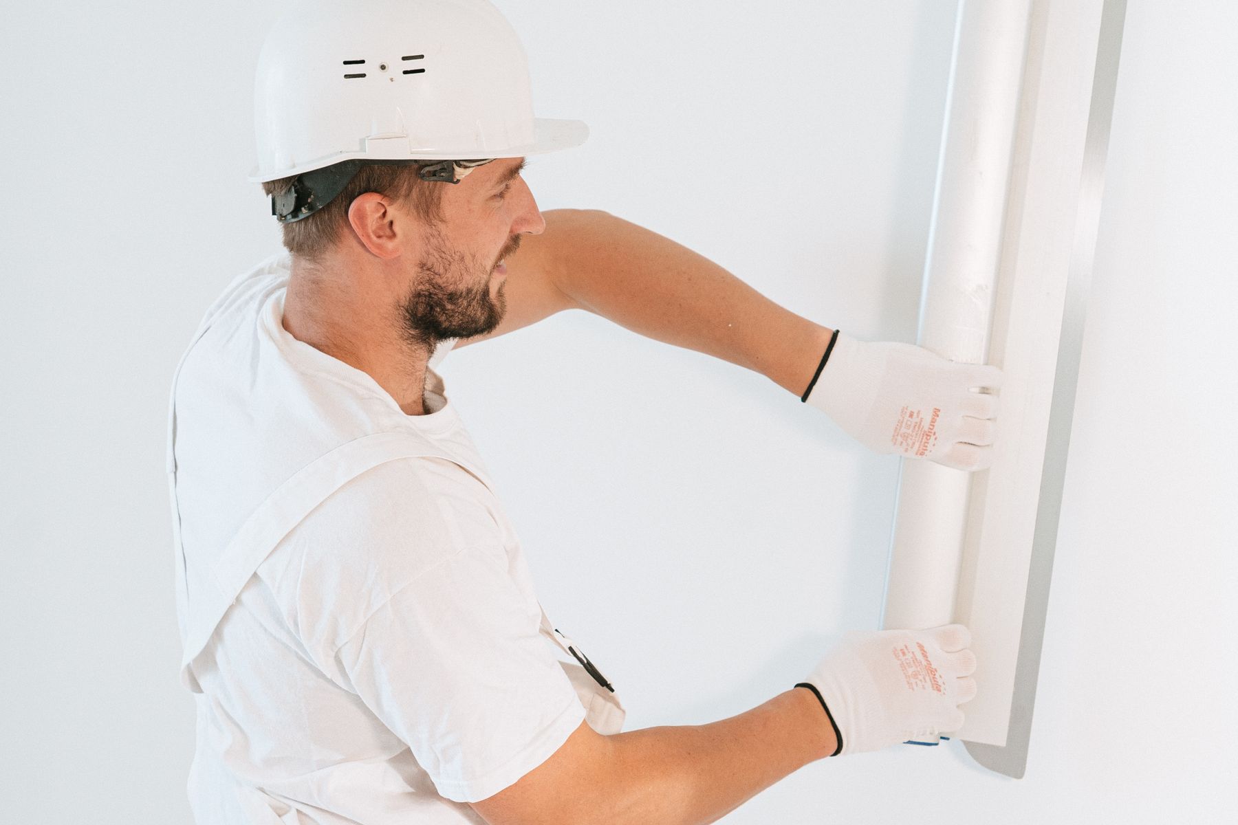 Construction worker fitting a drywall panel inside a building